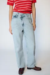 Jeans de tiro alto con diseño de cintura cruzada, cinco bolsillos y pernera recta con bajo sin costura. Cierre frontal con cremallera y botones.