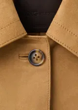 Chaqueta corta de piel caprina en color tostado, con cuello camisero, cierre frontal de botones y bolsillos de parche con solapa en el pecho.