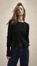 Remera de punto acanalado color beige, con silueta ajustada al cuerpo, cuello redondo y mangas largas. Presenta un detalle de volado en el ruedo confeccionado en lino de tono más claro, que aporta movimiento y un toque romántico a la prenda.