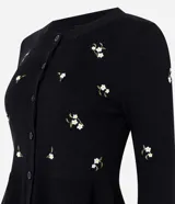 Cardigan negro de punto con bordado floral delicado, mangas largas, escote redondo, cierre frontal con botones y diseño peplum en la cintura.