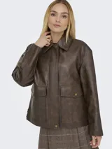 Campera de cuero sintético en color marrón oscuro, con cuello camisero, cierre frontal oculto con botones a presión y bolsillos delanteros con solapa. Presenta un corte holgado y diseño minimalista.