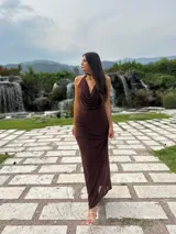 Vestido largo de microtul color marrón, con escote buche y cuello halter regulable. Presenta un diseño ajustado al cuerpo con forro interno corto.