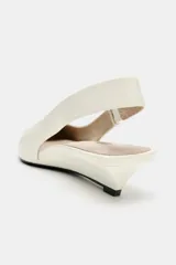 Zapato destalonado de piel color blanco, con tira trasera elástica, tacón de mini cuña y acabado en punta fina.