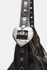 Bolso de hombro formato shopper con acabado efecto cuero desgastado. Cuenta con asa ajustable mediante hebilla metálica y detalle de tachas, cierre principal mediante imán y bolsillo interior con cremallera.