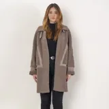 Tapado de textura tipo corderito en color taupe, con diseño de corte recto y largo. Presenta detalles de paneles lisos en los laterales y en las mangas, cuello con solapas y cierre frontal.