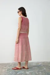 Pollera midi de tejido de punto a rayas verticales en color rojo y crudo, con cintura elástica.