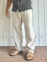 Pantalón de lino color beige, de corte ancho y relajado, con cintura ajustable mediante cordón.