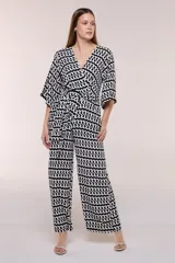 Enterito de calce relajado con caída fluida, escote en V cruzado estilo wrap, mangas tres cuartos estilo kimono y pantalón wide leg. Cuenta con cinto textil a tono para anudar en la cintura y bolsillos laterales, con diseño estampado geométrico en blanco y negro.