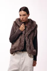 Chaleco acolchado color marrón con terminaciones de piel sintética en los bordes y cuello, aportando volumen y textura.