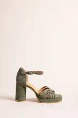 Sandalia de taco alto cilíndrico y plataforma, confeccionada en gamuza color verde militar. Presenta tiras cruzadas en la parte delantera y tira ajustable al tobillo con hebilla metálica.