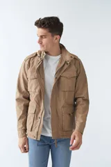 Campera de gabardina verde militar con capucha desmontable y ajustable, cierre frontal con cremallera y múltiples bolsillos con solapa.