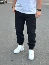 Pantalón jogger cargo de color negro, con bolsillos laterales en las piernas y puños elásticos en los tobillos.