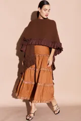 Falda larga de lino color tostado, con diseño de volados escalonados decorados con detalles brillantes en los bordes. Presenta una silueta fluida y cintura alta.