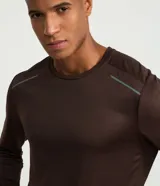 Remera deportiva de manga larga con cuello redondo, confeccionada en tejido técnico Dry Fit. Presenta un diseño liso con sutiles detalles reflectantes en los hombros.