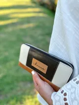 Billetera grande con cierre metálico, confeccionada en cuero. Presenta un diseño de bloques de color: negro texturado en el centro, beige texturado a los lados y cuero marrón liso en la parte inferior. Incluye un parche de cuero con la inscripción "chawie".