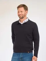 Remera de punto de manga larga con cuello tipo polo y cierre frontal de botones. Presenta un diseño liso en color azul marino con un pequeño detalle de etiqueta en el ruedo.