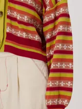 Cardigan crop de punto de algodón con mangas semi-abultadas, hombros caídos y puños acanalados. Presenta un diseño de rayas horizontales multicolor con gráficos en miniatura y cierre frontal de botones.