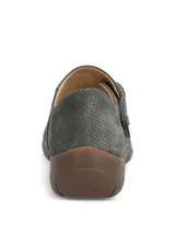 Zapato gris de cuero con perforaciones, empeine cerrado, ajuste con tira de velcro lateral y suela de goma marrón.