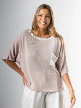 Remera tejida color crema con cuello redondo y bolsillo frontal verde.