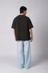 Remeron de corte oversized con cuello redondo y mangas cortas. Presenta un acabado de tela con efecto desgastado y costuras visibles en los bordes, con una etiqueta pequeña en el lateral inferior.