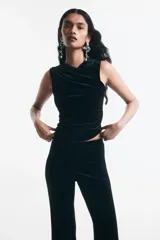 Top sin mangas de velour negro, ajustado al cuerpo, con escote cruzado drapeado y frunces laterales.