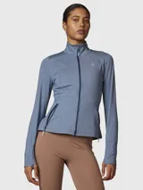 Campera deportiva de entrenamiento con cierre frontal completo, cuello alto y mangas largas con orificio para pulgar. Confeccionada en tejido técnico suave de color azul denim melange, cuenta con bolsillos laterales con cierre y costuras reforzadas.