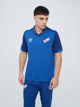 Remera polo deportiva Umbro del Club Nacional de Football, color azul con cuello en V y detalles en rojo y blanco. Incluye el logo de Umbro y el escudo del club.