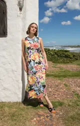 Vestido midi sin mangas con corte recto y tajos laterales en el ruedo. Presenta un estampado floral multicolor sobre base negra y cierre con botón en la espalda.