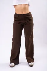 Pantalón de corte wide leg en color marrón, confeccionado en tejido con elastano. Presenta tiro medio, cierre frontal con botón y bolsillos laterales.