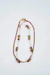 Set de dos collares de diseño artesanal. El primer collar combina cuentas rojas facetadas con cubos dorados. El segundo collar presenta cuentas transparentes pequeñas intercaladas con grupos de piedras naturales planas en tonos vibrantes como verde, naranja, amarillo, fucsia y azul.