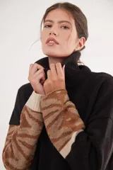 Polera de calce relajado confeccionada en lana, con cuello alto y mangas largas que presentan un diseño jacquard de arabescos y rayas en tonos contrastantes.