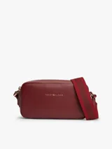 Cartera bandolera Tommy Hilfiger modelo Essential de color bordó, con acabado liso, cierre de cremallera y correa ajustable de jacquard. Presenta el logo y la inscripción de la marca en bajo relieve en la parte delantera.
