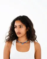 Collar de cuentas cilíndricas en tonos azules y negros, con un dije central de dos estrellas esmaltadas en azul con borde plateado.