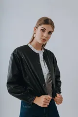 Campera bomber de cuero color marrón, con mangas abullonadas, puños elásticos y cierre frontal con botones a presión.