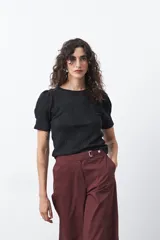 Remera negra de manga corta con textura floral en relieve. Presenta cuello redondo y mangas ligeramente abullonadas que aportan estructura al diseño.