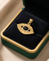 Dije de acero dorado con diseño de ojo estilizado y piedra central negra ovalada.