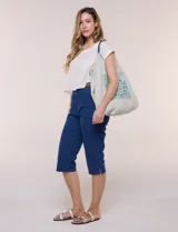 Bolso tote amplio color beige, con cordón de ajuste superior, asas de cordada trenzada bicolor y detalle de bolsillo con bordado central de diseño paisley en tonos azules.