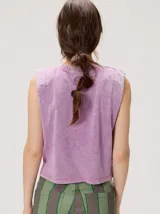 Musculosa crop de algodón con efecto acid wash en color lila, cuello redondo, hombreras marcadas y pequeño bordado central en el pecho.