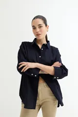 Camisa color crudo, de corte clásico, con cuello camisero, cierre frontal con botones y mangas 3/4 con trabillas.