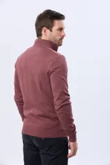 Buzo de tejido fino en hilo de algodón, color rosado, con cuello alto y cierre frontal parcial con detalle en cuero. Presenta puños y ruedo acanalados y un pequeño logo bordado en el pecho.