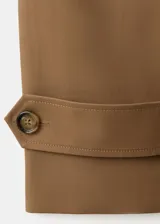Chaqueta corta de algodón color marrón tostado, con cuello alto, cierre frontal de botones, bolsillos ribeteados y mangas largas con trabillas ajustables en los puños.