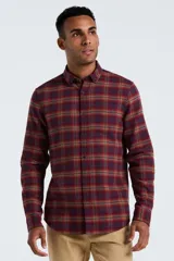 Camisa de manga larga confeccionada en tela de franela con estampado de cuadros en tonos bordó, naranja y azul. Presenta cuello con botones, cierre frontal abotonado y bolsillo en el pecho.