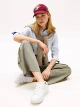 Zapatillas de tenis de corte bajo de la marca Tommy Hilfiger, confeccionadas en piel napa de color blanco. Presentan cordones, punta redonda, suela de goma y detalles distintivos como un pequeño logo esmaltado en el lateral y el nombre de la marca en la lengüeta.