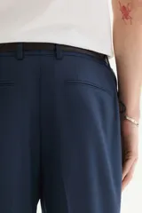 Pantalón de traje de corte ajustado, con cierre frontal y corchete oculto. Presenta bolsillos laterales, bolsillos traseros ribeteados y raya marcada en el frente.