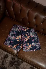Short deportivo con estampado abstracto multicolor sobre fondo oscuro, diseñado con aperturas laterales para mayor comodidad durante el ejercicio. Presenta cintura elástica y está confeccionado en una mezcla de rayón, nylon y spandex.