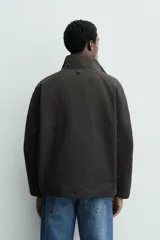 Cazadora de corte regular confeccionada en tejido mezcla de algodón. Presenta cuello subido, cierre frontal con cremallera oculta por solapa con botones a presión, bolsillos laterales de vivo y bajo ajustable con elásticos ocultos. Incluye forro interior a contraste.