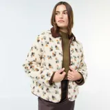 Chaqueta de sherpa color crema con estampado floral en tonos marrones, amarillos y verdes. Tiene cuello camisero y ribete de pana marrón.