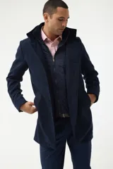 Gabán azul marino con cuello alto y pechera desmontable con cierre.