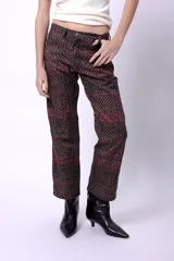 Pantalón de corte recto con estampado de espiga y líneas cruzadas en tonos marrones, rojos y azules. Presenta cierre frontal con botón y bolsillos laterales.