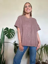 Chaleco tejido color verde oliva, con cuello en v y diseño de trenzas y ochos. Silueta oversize.